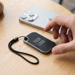 Traxo Bluetooth locator device, black panel with silver metal frame, front view