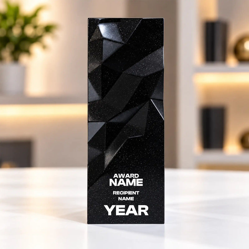Black geometric faceted crystal award column on a desk