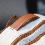 Beige Voxtra travel backpack, front three-quarter view with tan leather trim